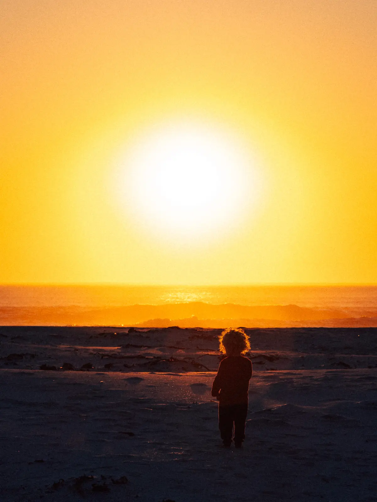 A child watching the sun go down over the sea