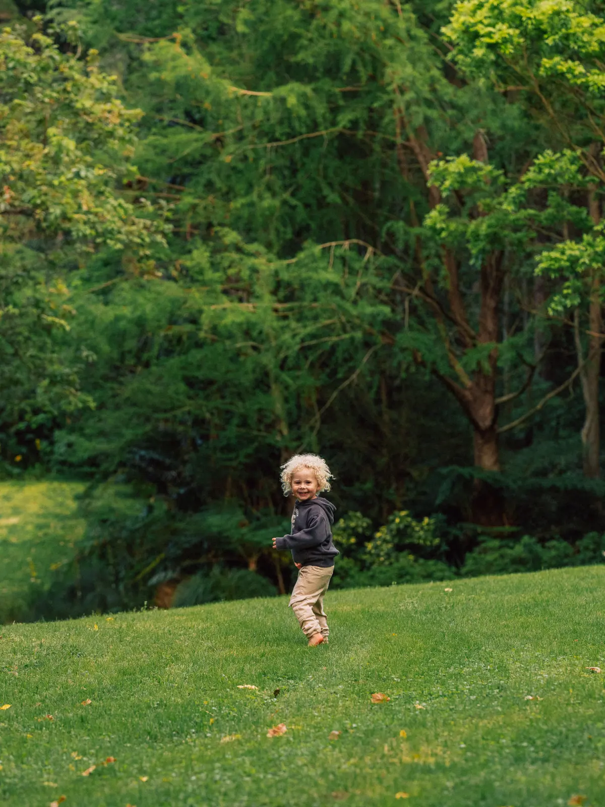 A child running across grass towards the trees